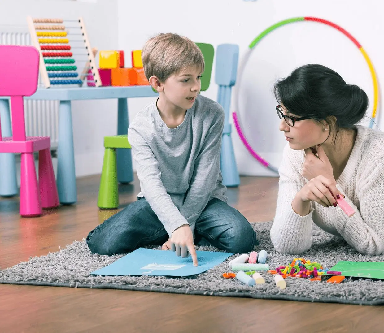 image Child and teacher discussing at playroom table.